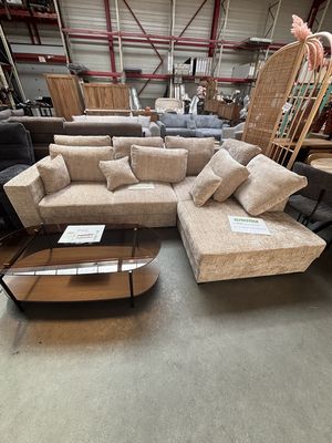 Canapé d’angle beige garni de coussins et table basse ovale en bois