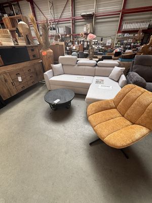 Canapé d’angle blanc cassé et fauteuil pivotant orange dans l’entrepôt