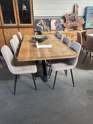Table de repas en bois massif et chaises capitonnées beiges devant une enfilade